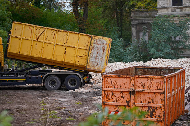 truck on a construction site picking up a container and dumping building rubble